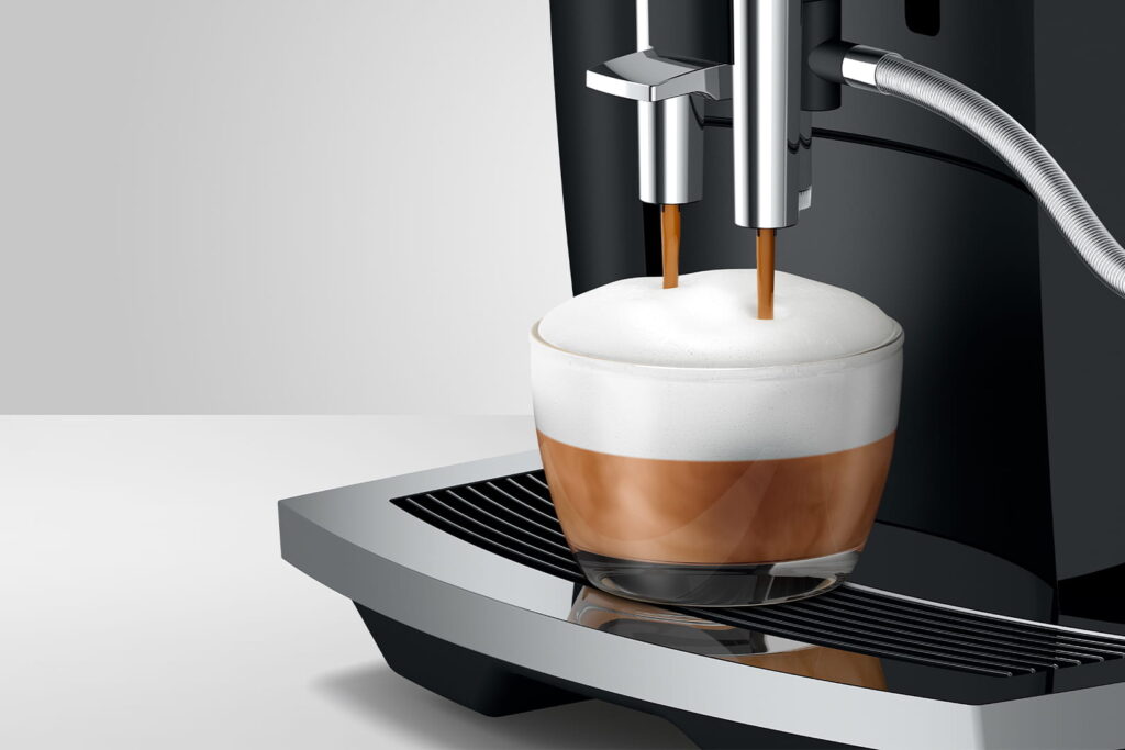 Jura E6 (EC) Kaffeevollautomat in Piano Black, Detailansicht Cappuccino mit Milchschaum