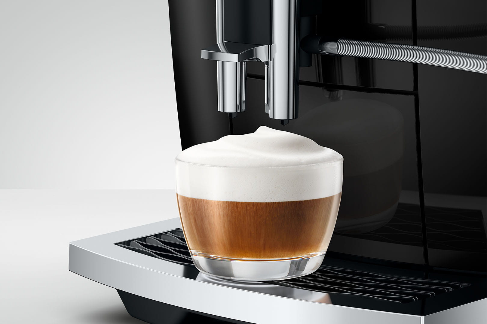 Jura E6 (ED) Kaffeevollautomat in Piano Black, Detailansicht Cappuccino mit Milchschaum
