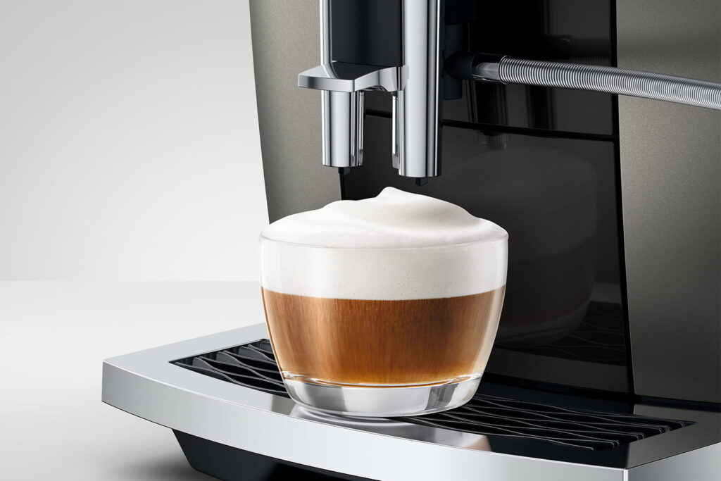 Jura E6 (ED) Kaffeevollautomat in Dark Inox, Detailansicht Cappuccino mit Milchschaum